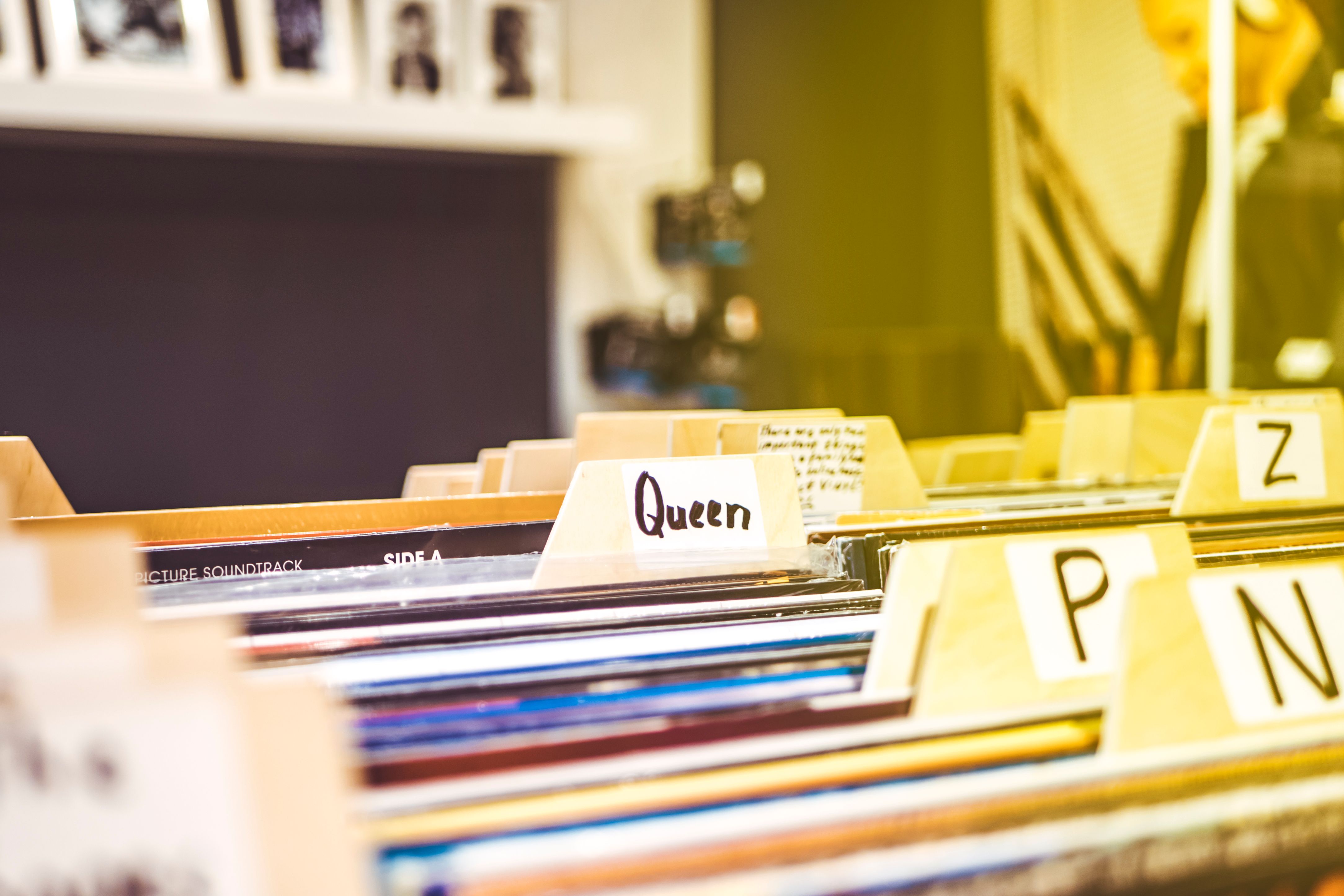 Close-up view of alphabetically organized vinyl records in an indoor music store setting.