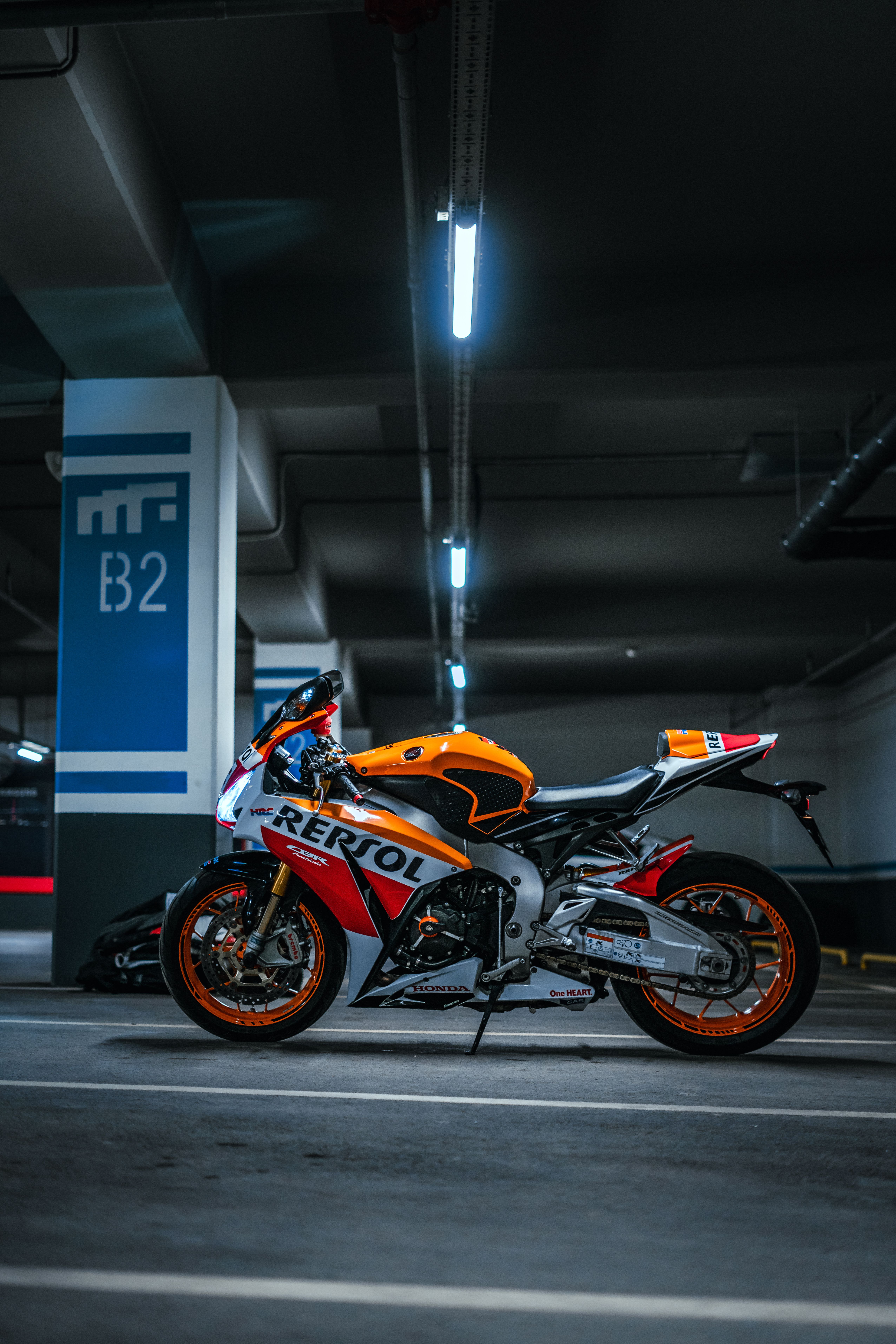 Orange and white sports motorcycle parked in an underground garage.