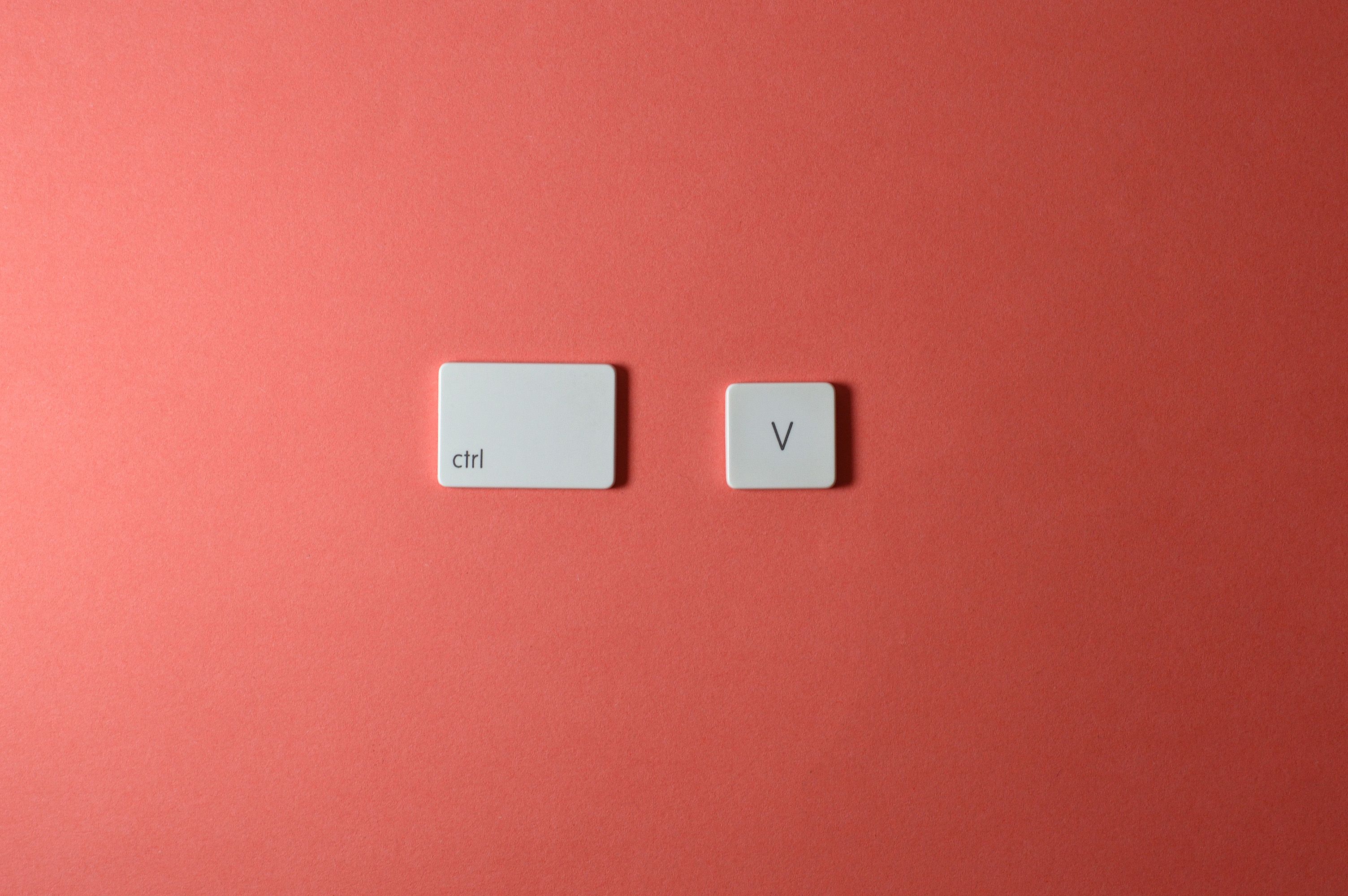 Minimalist composition of Ctrl and V keyboard keys on a coral background, perfect for tech-themed designs.