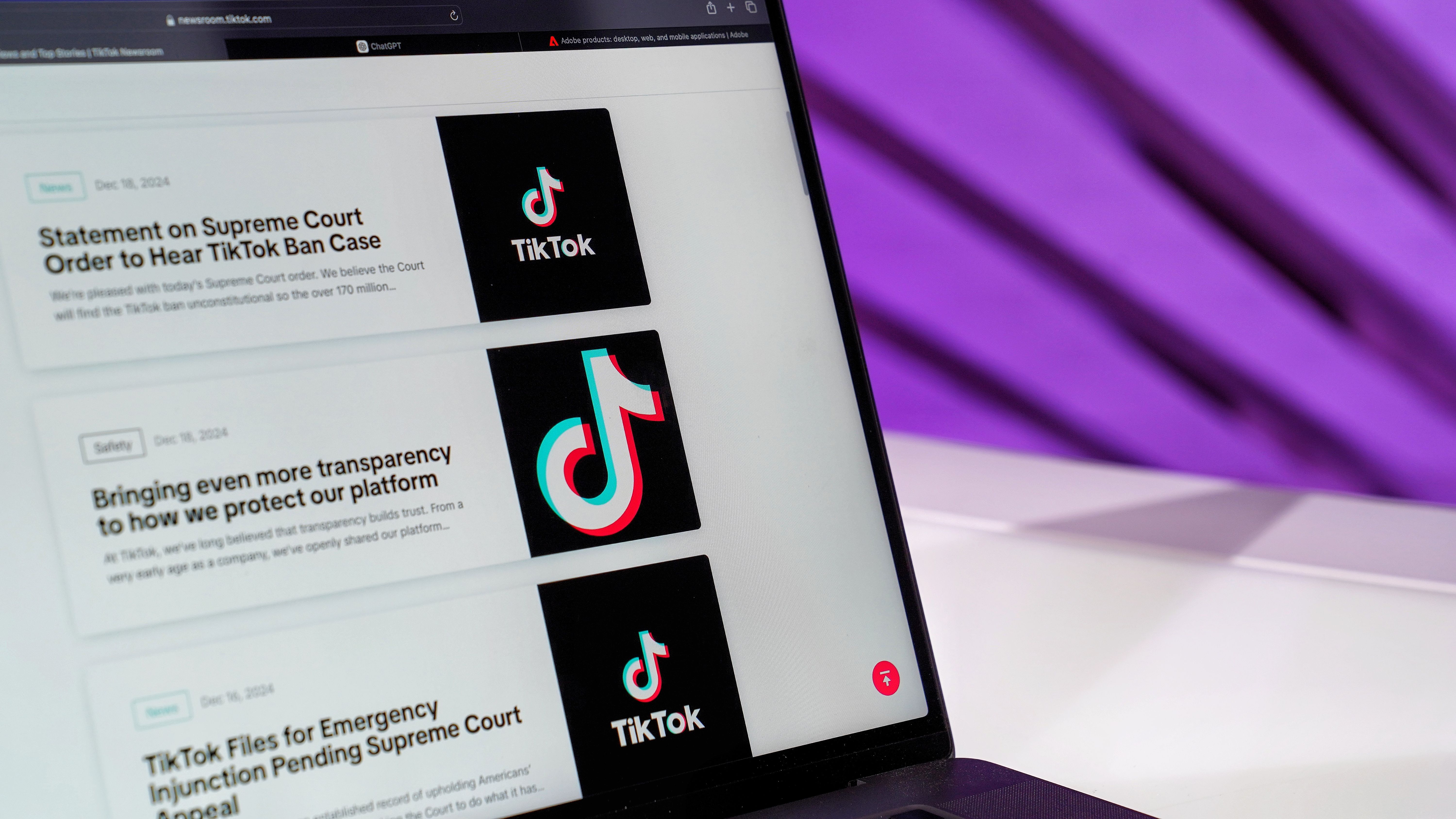 Close-up of laptop screen showing TikTok news articles with a purple background.