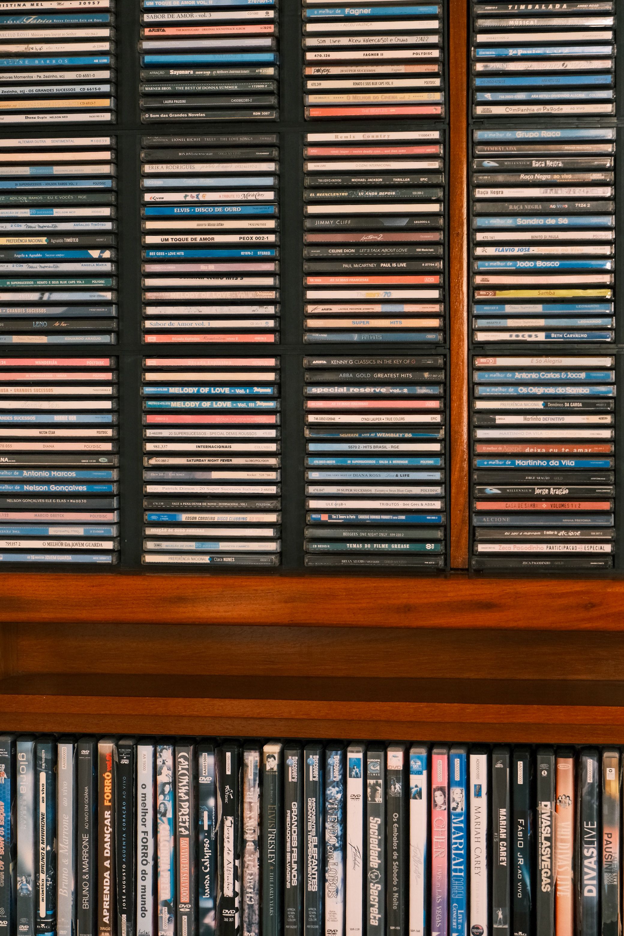 A neatly arranged collection of CDs displayed on a wooden shelf, showcasing various music genres.