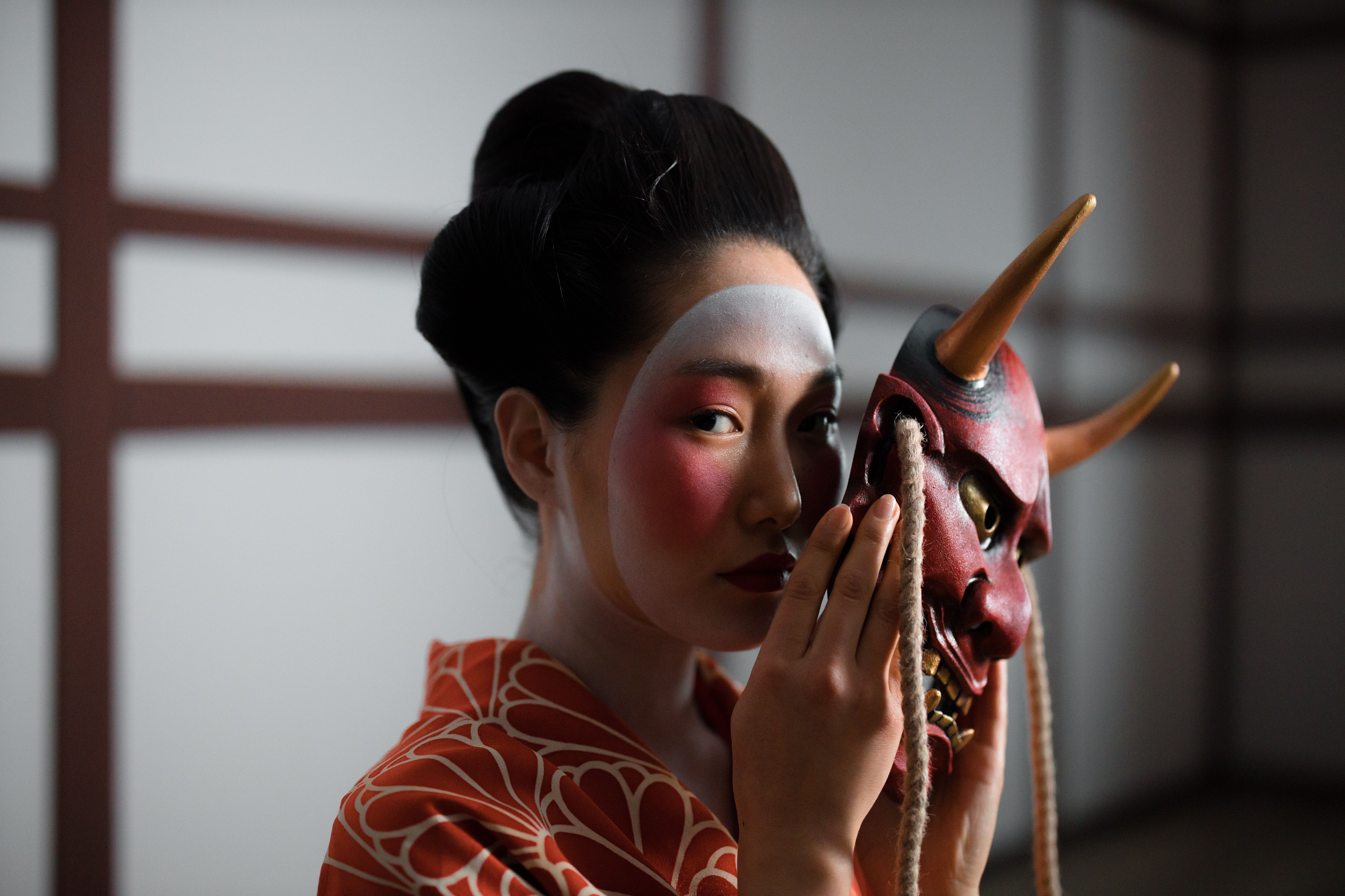 Captivating portrait of a geisha holding a Hannya mask, embodying Japanese culture and tradition.