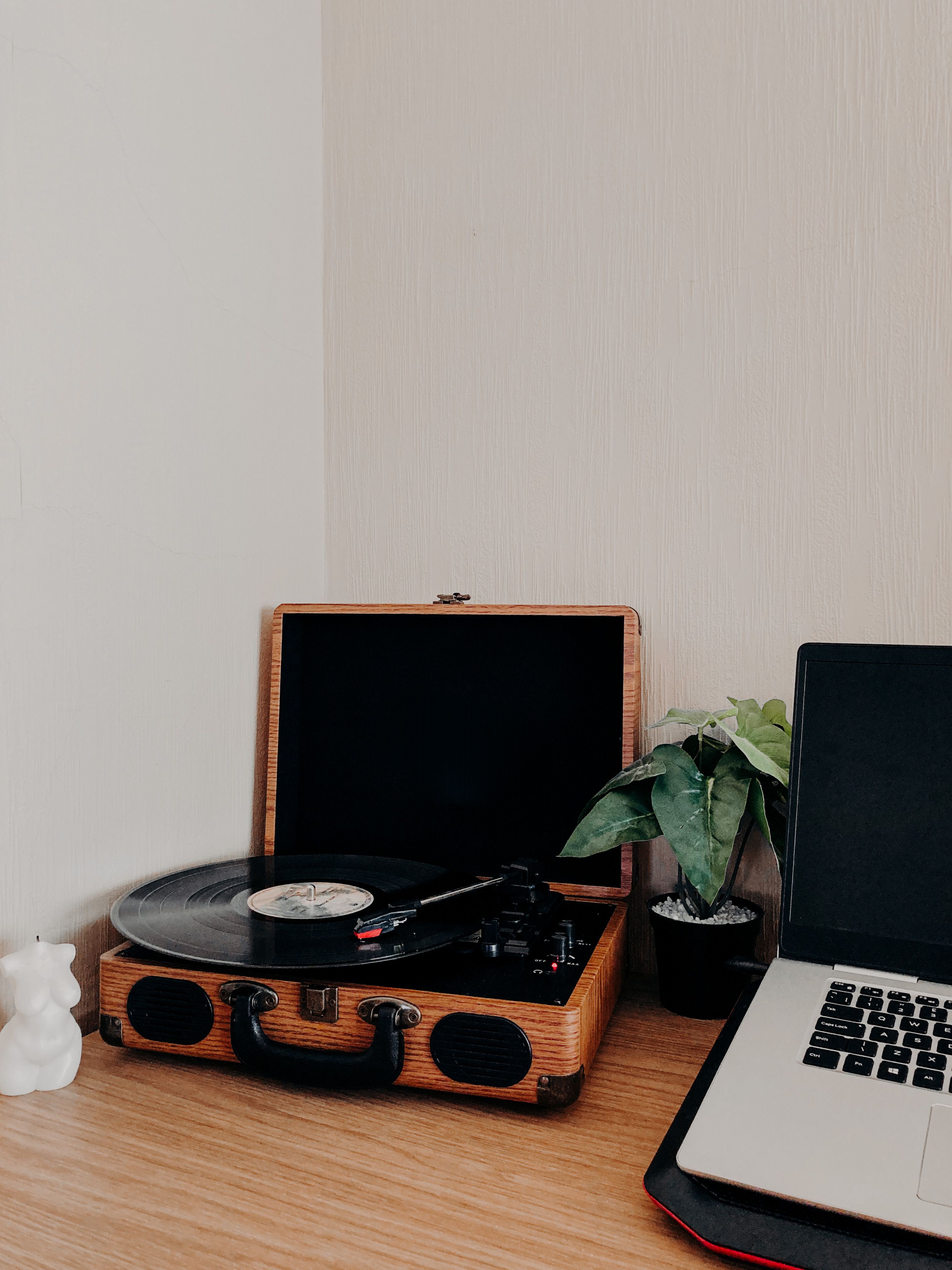 A vintage turntable and laptop on a minimalist wooden desk, adding a retro touch to a modern workspace.